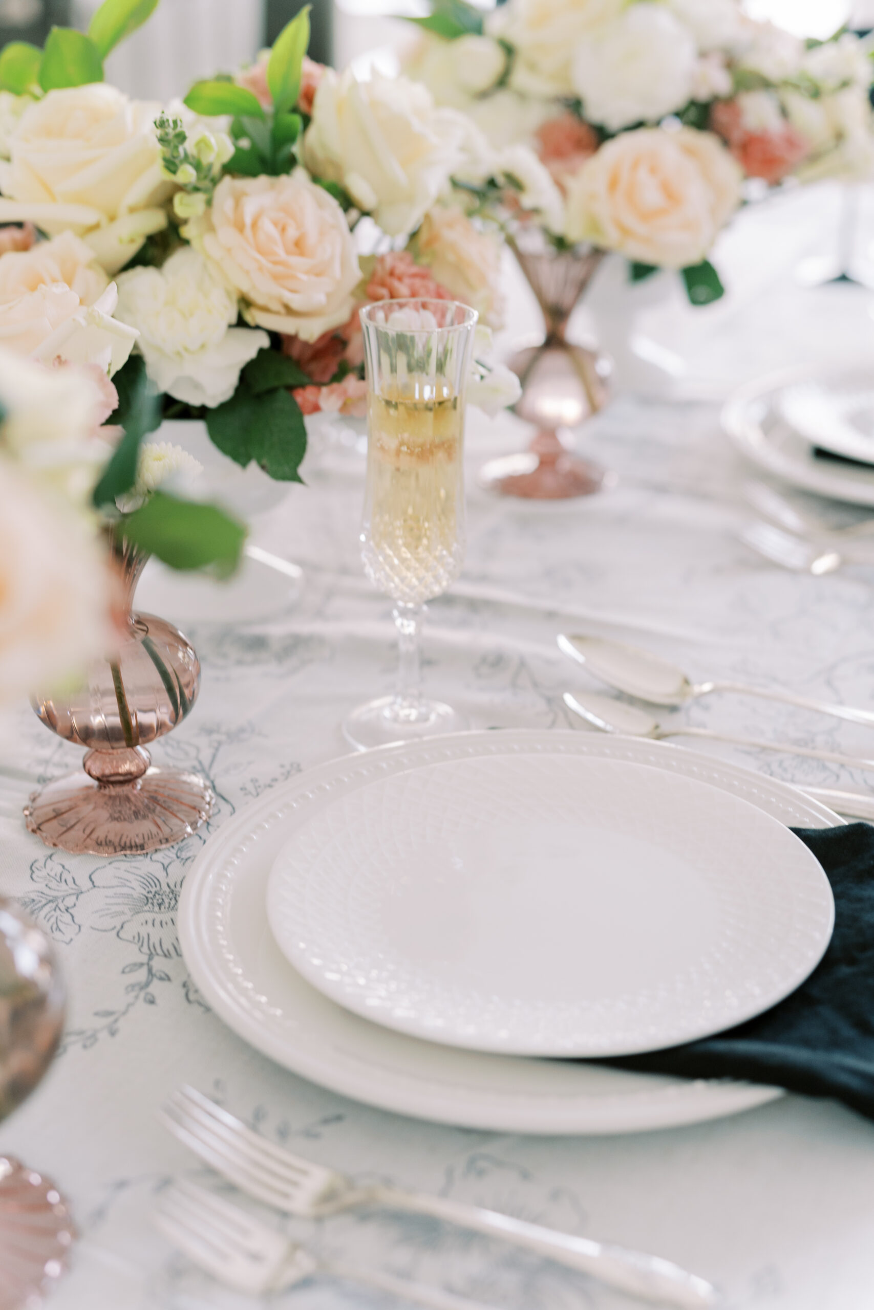 A place setting with white plates, a black napkin, and a glass of champagne